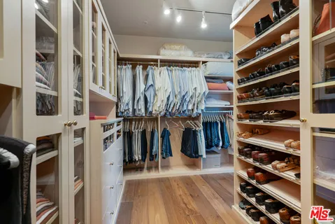 a view of walk in closet with clothes and shoes