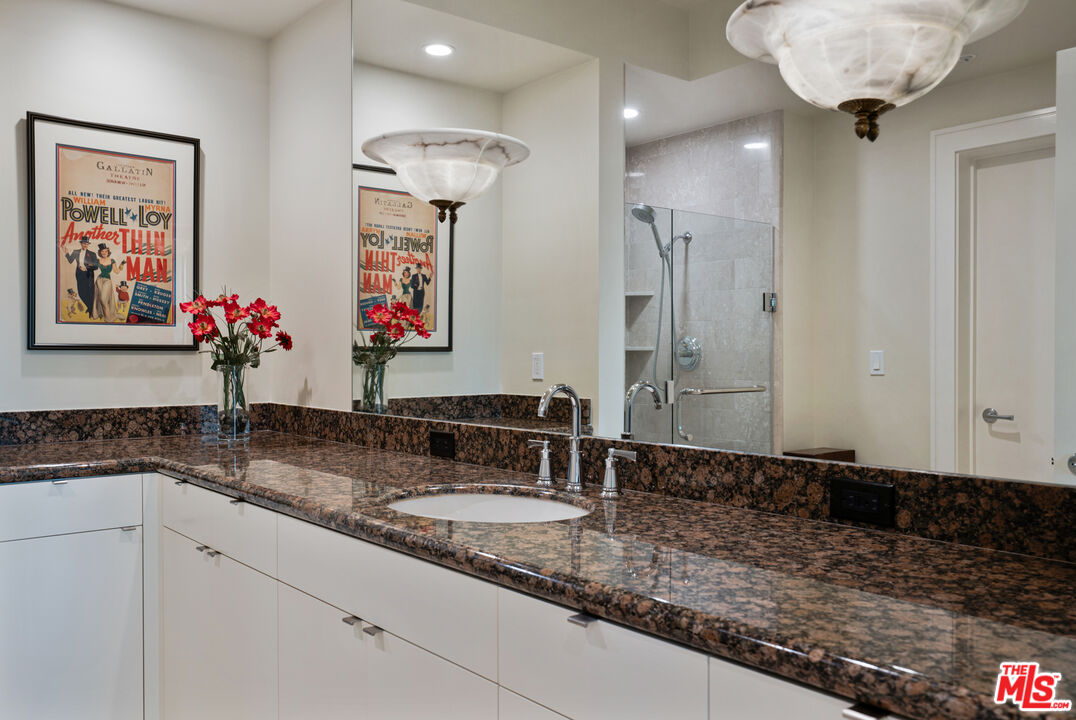 10580 Wilshire Boulevard, Unit 23NE Los Angeles, CA 90024 - Photo 33 of 42 a bathroom with a granite countertop sink and a mirror