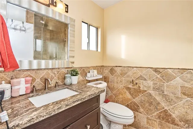 a bathroom with a granite countertop sink a mirror and a toilet