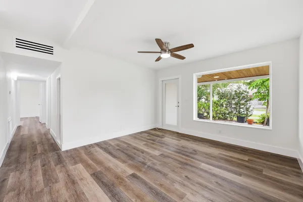 a view of empty room with wooden floor and fan