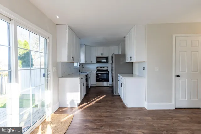 a kitchen with a refrigerator a stove top oven and white cabinets