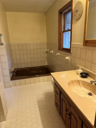 a bathroom with a tub sink and mirror