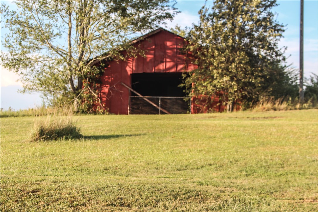 757 Belle Shoals Road Pickens, SC 29671 - Photo 7 of 31 A classic red barn stands against a blue sky, surrounded by verdant fields and mature trees.