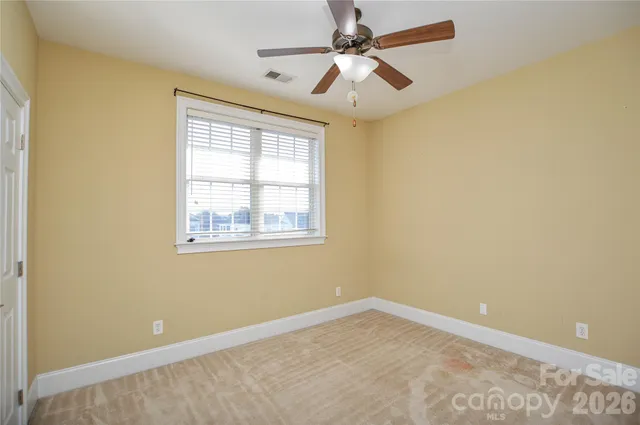 an empty room with a window and a fan