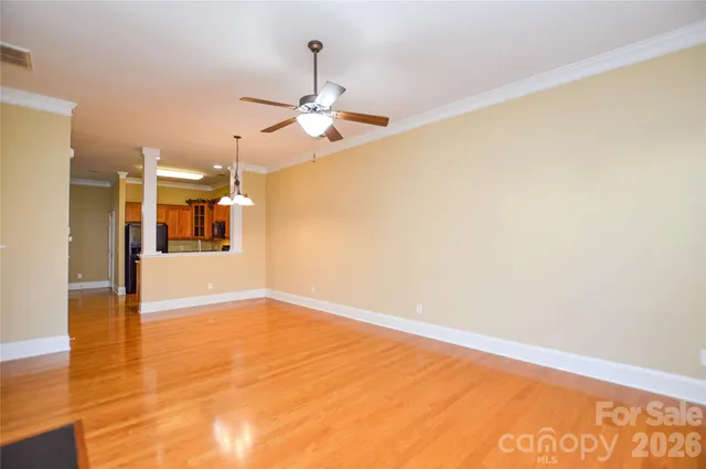 a view of empty room with wooden floor and ceiling fan