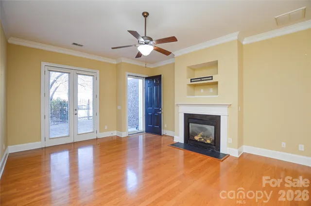 a view of an empty room with chandelier fan and fire place
