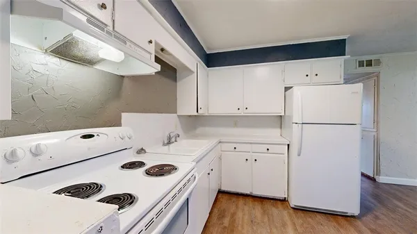 a kitchen with a white stove top oven and a refrigerator