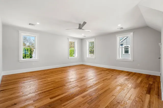 a view of empty room with wooden floor and fan