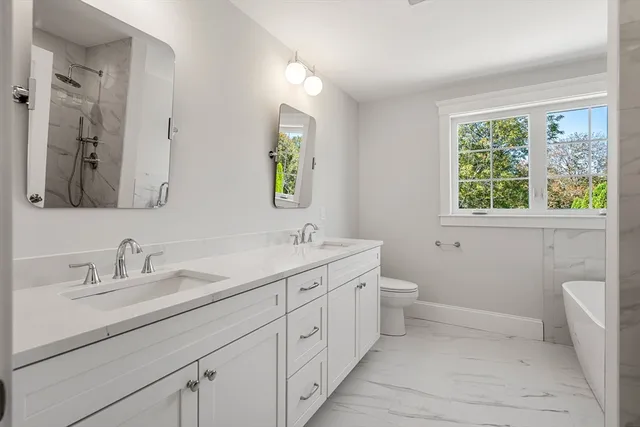 a bathroom with a double vanity sink toilet and a window