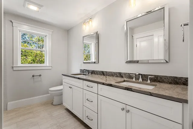 a bathroom with a granite countertop toilet sink and mirror