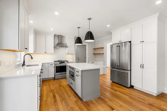 a kitchen with stainless steel appliances granite countertop a refrigerator a sink dishwasher a stove and white countertops with wooden floor