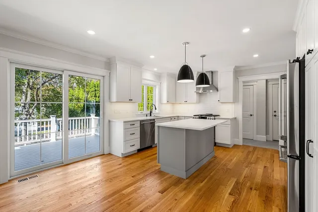 a large kitchen with a large window a sink stainless steel appliances and cabinets