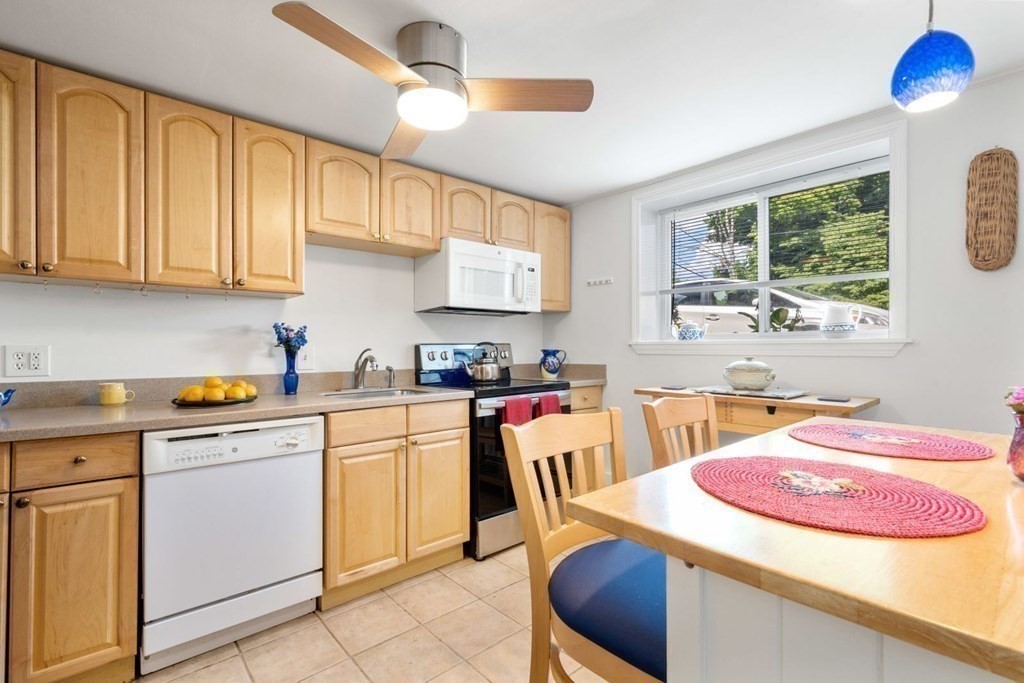 64 Bryon Road, Unit B641 Boston, MA 02467 - Photo 9 of 26 a kitchen with stainless steel appliances kitchen island granite countertop a sink a stove a refrigerator a microwave oven with white cabinets and wooden floor
