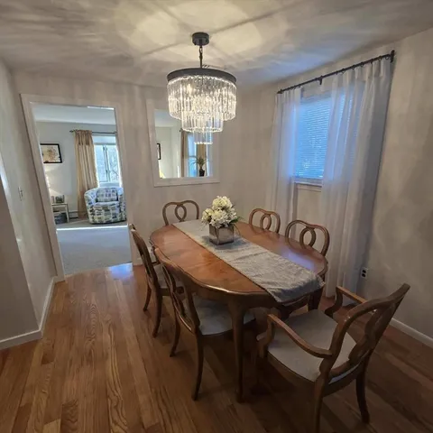 a view of a dining room with furniture a chandelier and wooden floor