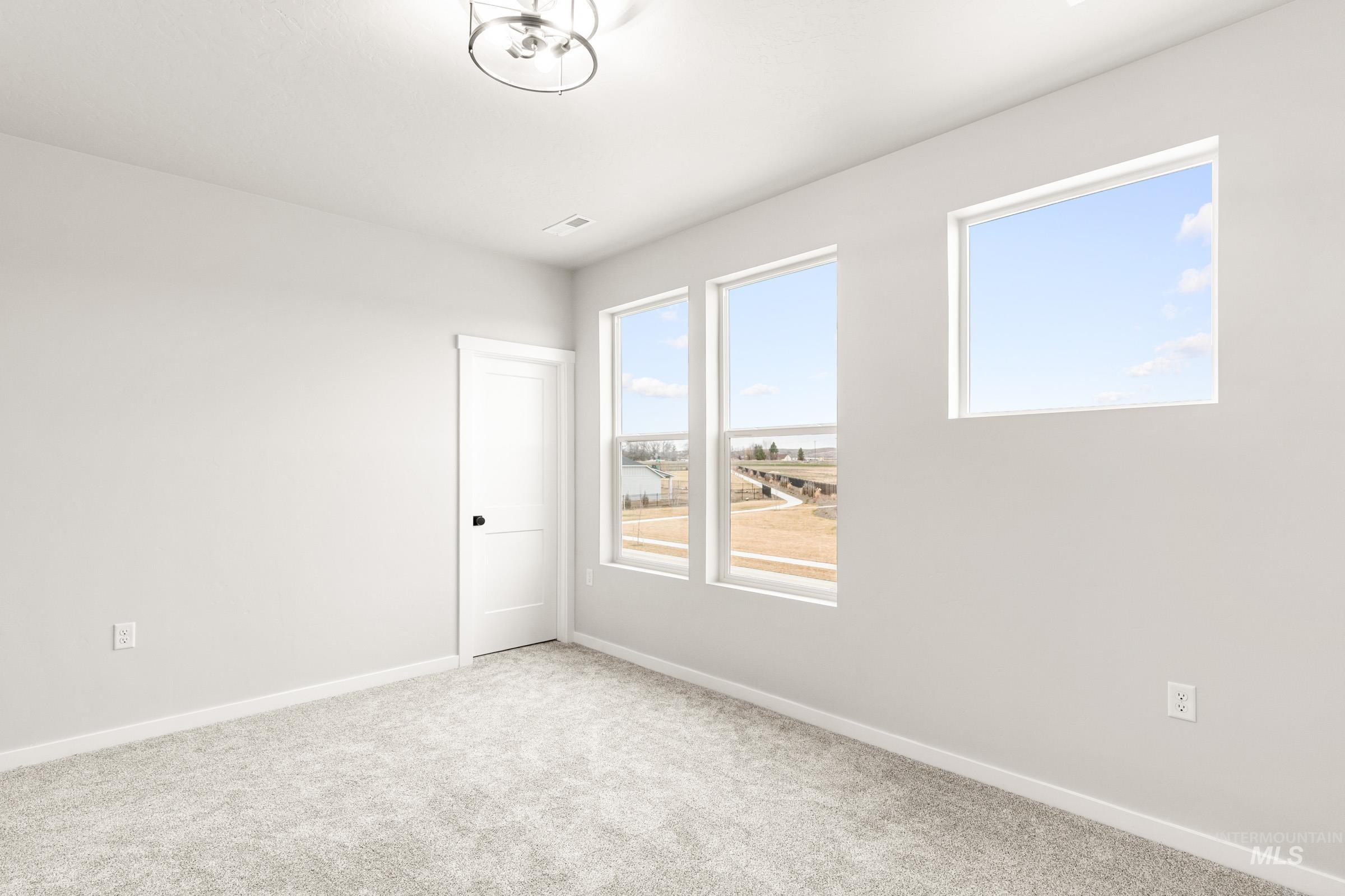 4227 East Rincon Drive Meridian, ID 83642 - Photo 25 of 31 Room featuring three large windows, light gray carpet, white walls, and a contemporary ceiling light fixture