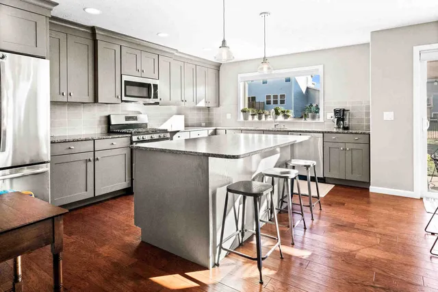 a kitchen with stainless steel appliances granite countertop a stove top oven a refrigerator a sink and a dining table with wooden floor