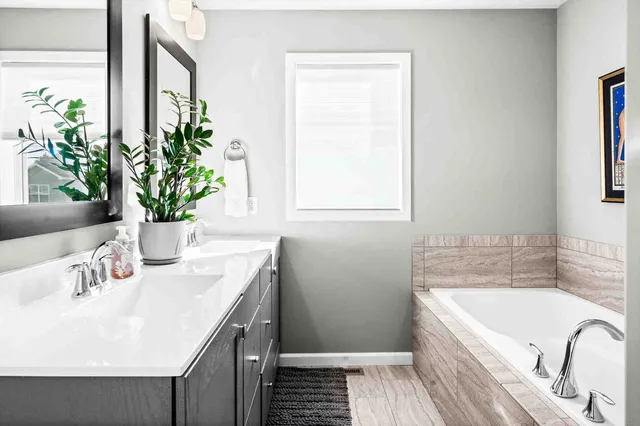 a bathroom with a granite countertop bathtub a sink and a window