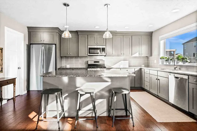 a kitchen with stainless steel appliances granite countertop a stove top oven a refrigerator a sink and chairs