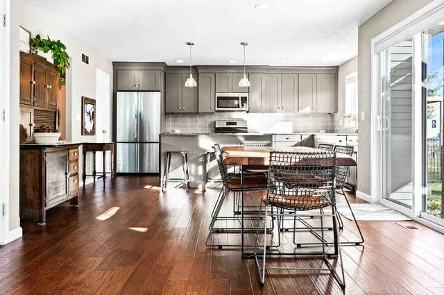 a kitchen with stainless steel appliances a dining table chairs stove refrigerator and cabinets