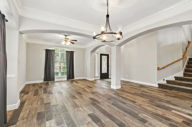 a view of an empty room with wooden floor and a chandelier
