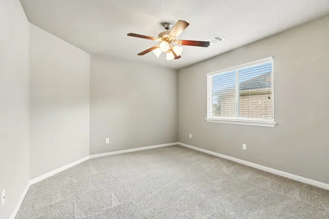 an empty room with windows and ceiling fan