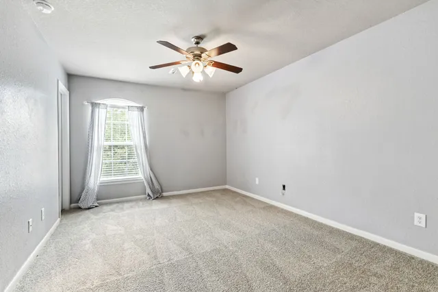 an empty room with windows and fan