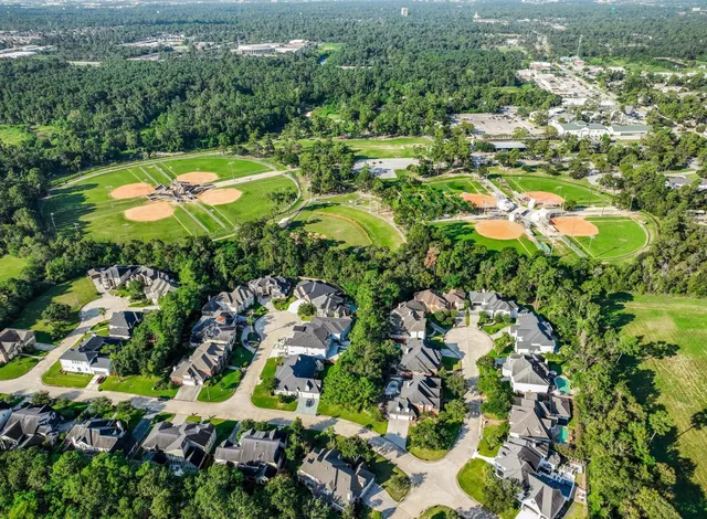 an aerial view of residential houses with outdoor space and trees
