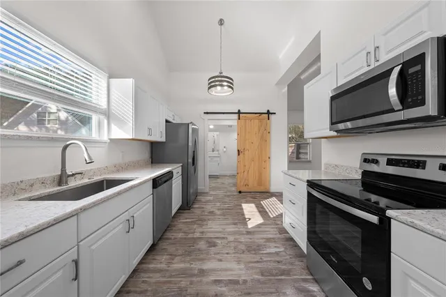 a large kitchen with stainless steel appliances granite countertop a stove a sink and a microwave