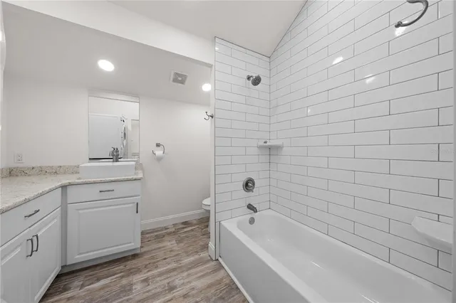 a bathroom with a granite countertop sink a toilet and bathtub