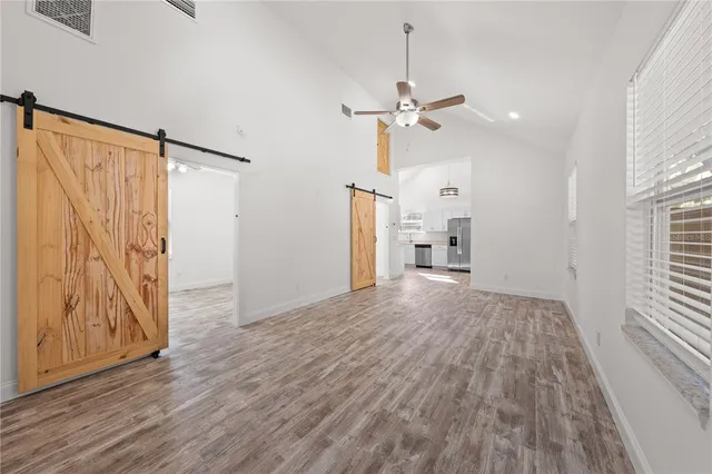 a view of empty room with wooden floor and fan