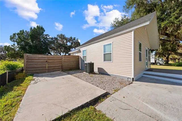 a view of backyard with wooden fence and large trees