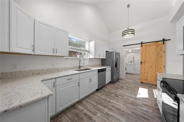 a kitchen with stainless steel appliances granite countertop a sink a stove cabinets and wooden floor