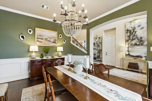 a room with a dining table wooden floor and a chandelier