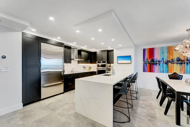 a kitchen with stainless steel appliances kitchen island granite countertop a refrigerator a stove a sink a dining table and chairs