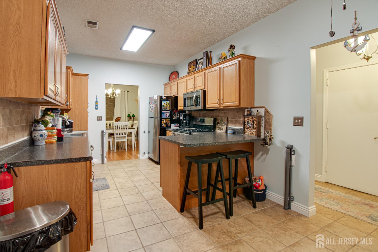 2 Fieldcrest Way Freehold, NJ 07728 - Photo 8 of 24 a kitchen with stainless steel appliances granite countertop a stove top oven a sink a dining table and chairs