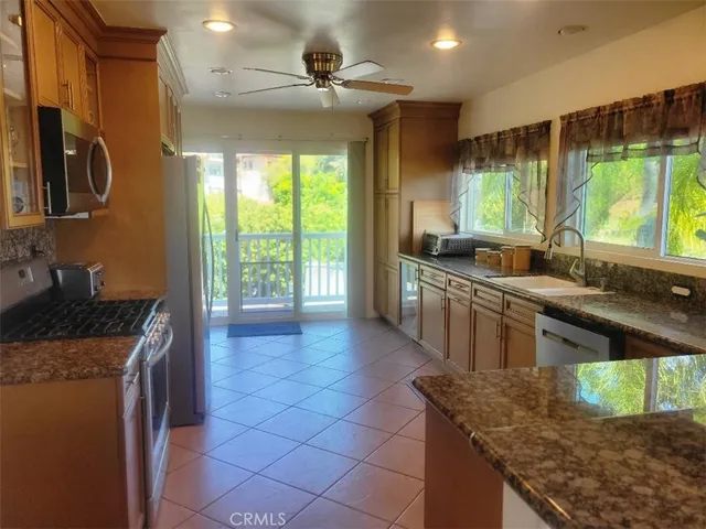 a kitchen with stainless steel appliances granite countertop a sink a stove and a wooden cabinets