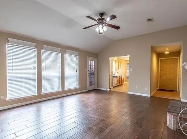 a view of an empty room with wooden floor and a window