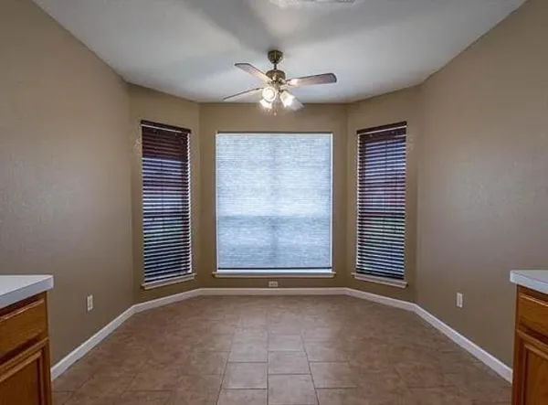 an empty room with windows and fan