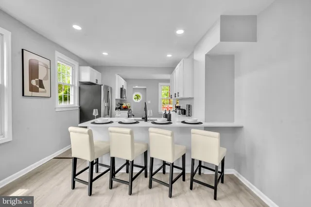 a kitchen with stainless steel appliances kitchen island granite countertop a dining table chairs and a refrigerator