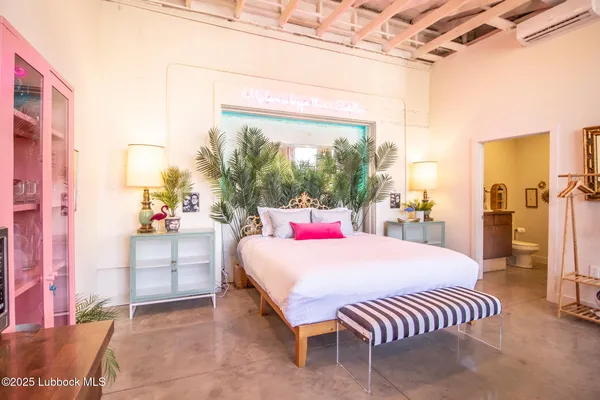 a bedroom with a bed a couch and dresser with wooden floor