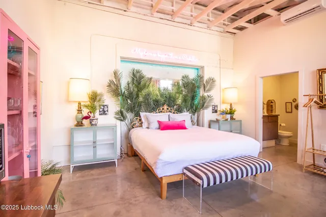 a bedroom with a bed a couch and dresser with wooden floor