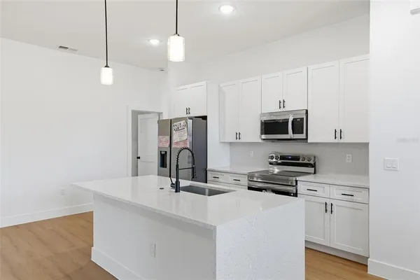 a kitchen with stainless steel appliances a stove a sink a refrigerator a center island and wooden floor