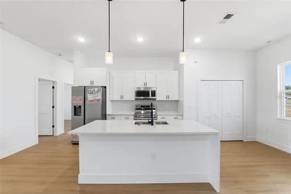 a large kitchen with stainless steel appliances kitchen island a large counter top and wooden floors