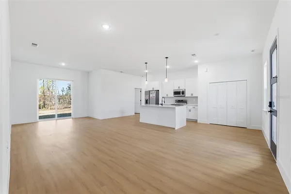 a view of an empty room with kitchen view and appliances