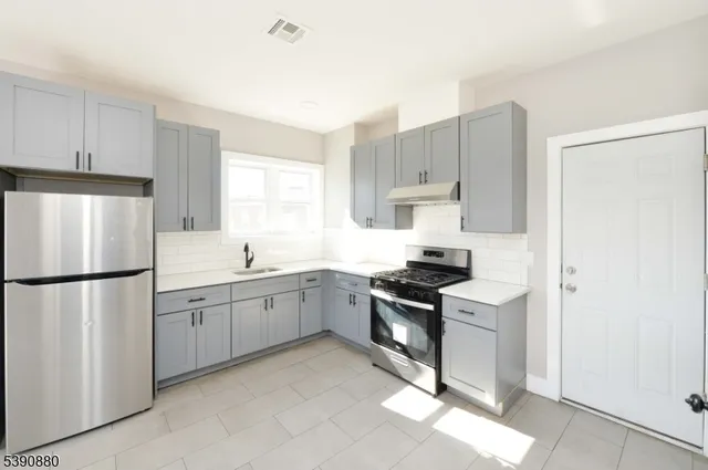 a kitchen with white cabinets a refrigerator and a sink
