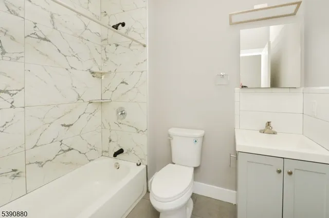 a bathroom with a toilet sink vanity tub and mirror
