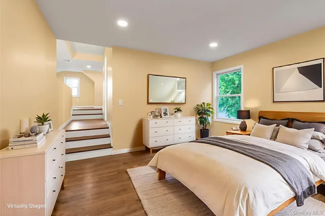 a spacious bedroom with a bed and a large mirror on the dresser