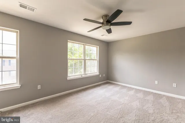 a view of a big room with windows and chandelier fan
