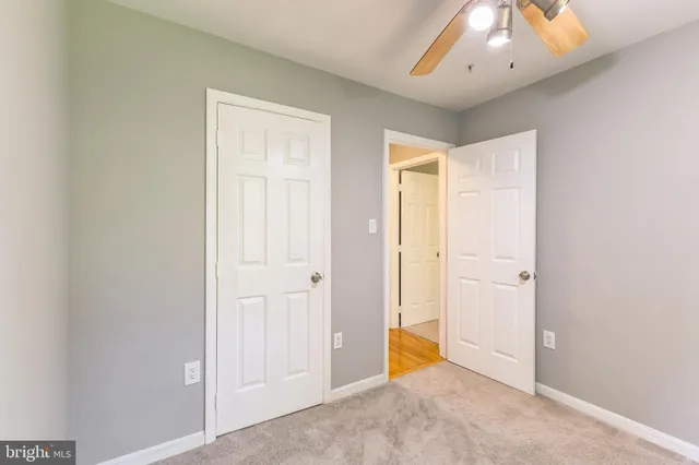 an empty room with a window and chandelier fan