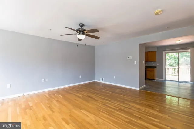 a view of an empty room with window and wooden floor